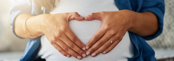Chiropractic Bellevue WA Pregnancy A pregnant woman making a heart shape with her hands over her belly.