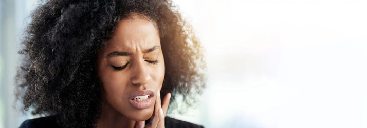 Chiropractic Bellevue WA Woman with Jaw Pain A woman holding her jaw in pain.