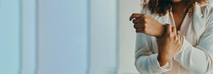 Chiropractic Bellevue WA Wrist Pain A woman holding her wrist, while wearing a white shirt.