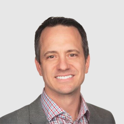 Dr. Mark Thompson smiling in a grey suit.
