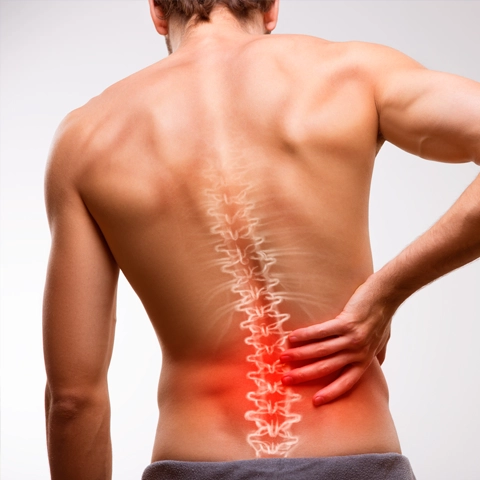 A man holding his back in pain. His spine is highlighted red.