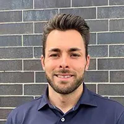 Dr. Jake Lipski smiling in front of a brick wall.